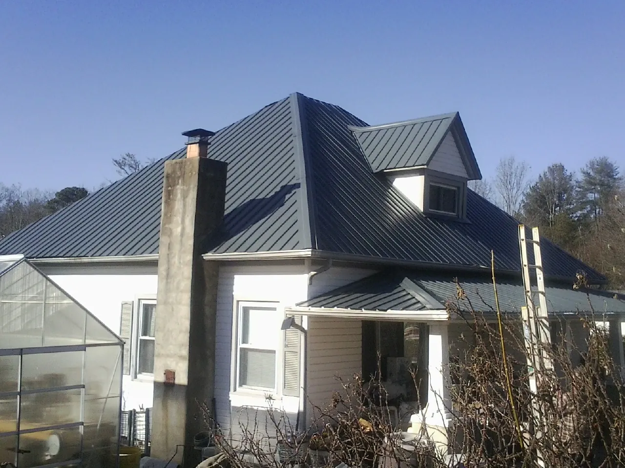Dark blue standing seam metal roof on a white farmhouse with dormer — Slate & Tile Roof Repair by Roofing Brothers in Endicott