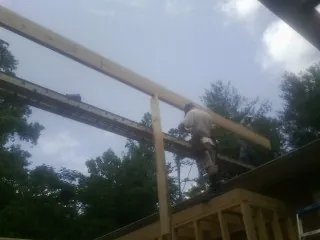 Carpenter setting a ridge beam over a new addition frame — Ice Dam Removal by Roofing Brothers in Endicott