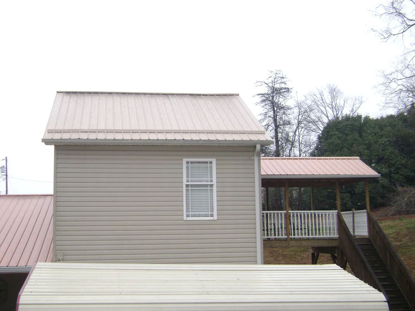 Tan metal roofs on a two story addition and attached porch, from a Roof Replacement job in Endicott