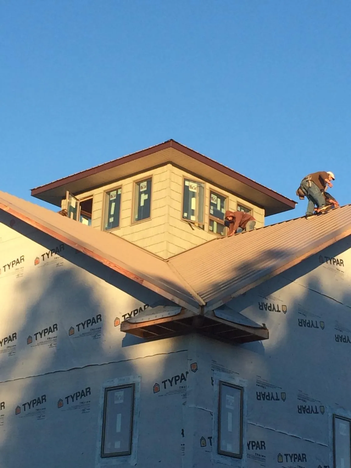 Roofers working around a rooftop cupola on a new metal roof at sunset — Roof Waterproofing in Endicott by Roofing Brothers